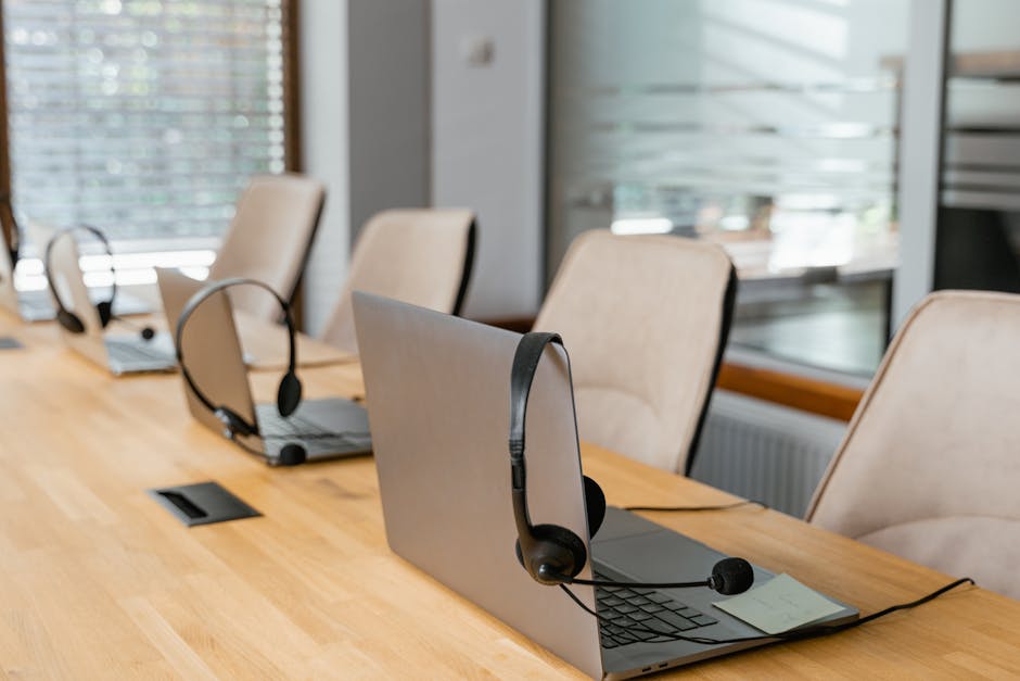 Row of laptops with headsets in a modern office environment ready for communication.